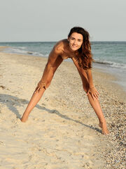Lorian provocativly poses by the sandy beach as she reveals her stacked, nude body
