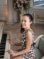 Ulia delightfully poses by the piano having fun with her bushy heart of her femininity